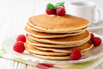 Pancakes with raspberry and mint on white wooden background