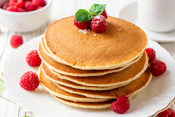 Pancakes with raspberry and mint on white wooden background