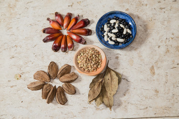 Composition with rustic pottery bowls of Lentils, chia seeds, and beans. Pinions and 'Castanha-do-Pará' nuts. Laurel Nobilis aromatic leafs