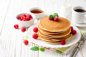 Pancakes with raspberry and mint on white wooden background