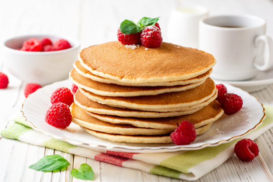 Pancakes with raspberry and mint on white wooden background