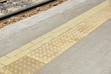 Fototapeta premium yellow tactile path for people with disabilities on the railway station platform