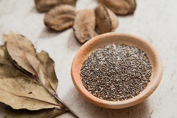 Composition with a small bowl of chia seeds and 'Castanha-do-Pará' nuts. Laurel Nobilis aromatic leafs