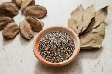 Composition with a small bowl of chia seeds and 'Castanha-do-Pará' nuts. Laurel Nobilis aromatic leafs