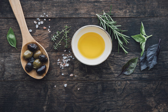 Food: Wooden background with a spoon of olives,himalayan salt,ol