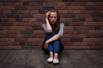 Fototapeta na wymiar Depressed teenager girl sitting alone on the floor in the dark room.