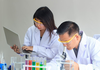 Young female and male scientist team working with laptop and microscope for science research laboratory.Concept Science and Medical image.