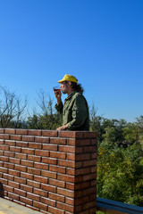 A construction worker interrupted his work and drinks coffee in the open air near the brickwork.