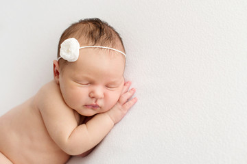 Sleeping newborn girl on a white background. Photoshoot for the newborn. 7 days from birth. A...