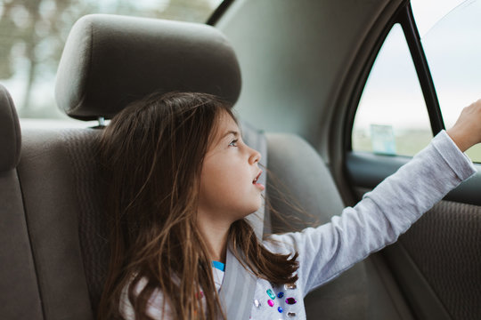 Young girl pointing out the window of automobile
