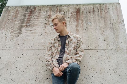 Young man with floral pattern shirt on a cityscape.