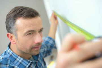 Man measuring wall with tape measure