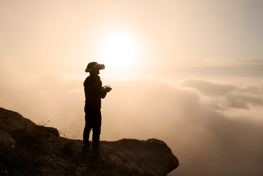 Man in vr glasses with remote controller in hands on edge of mou