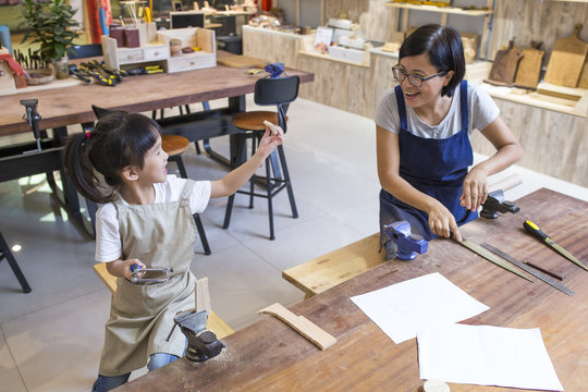 Asian womant with her kid doing carpenter job in the studio