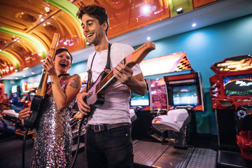 Excited couple holding gaming guitars in hand having fun