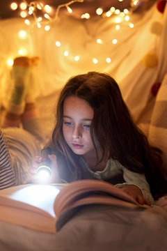 Young girl reading with flashlight