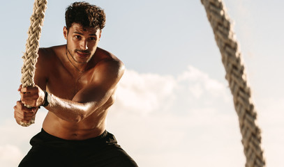 Man using battling rope for workout at the beach