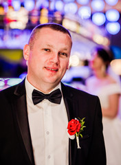 The groom  in the restaurant room. Bride in the background