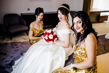 Beautiful bride and girlfriends are sitting on the bed