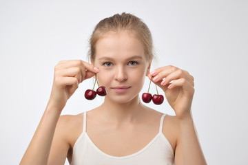 Portrait of european young woman holding red cherry. Concept of healthy vegan diet