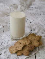 Homemade cookies with anise and cinnamon with a glass of milk on a white wooden background with a lace cloth