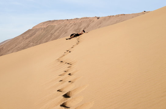Guy resting after climb to the enormous sand dune