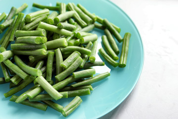 Plate with fresh cut green French beans on table, closeup