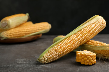 Tasty ripe corn cobs on grey table