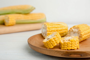 Plate with tasty sweet corn on wooden table