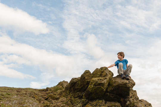 Tween boy sitting at the summit of a hill after his climb