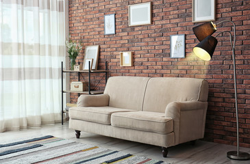 Modern living room interior with comfortable sofa near brick wall