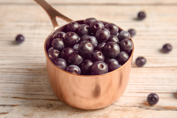 Dish with fresh acai berries on wooden table, closeup