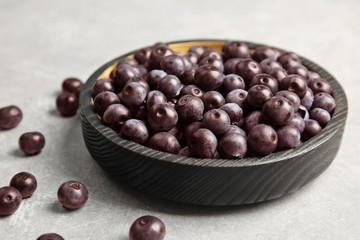 Plate with fresh acai berries on table