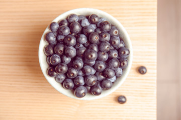 Bowl with fresh acai berries on table, top view