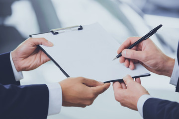 Close up Two Men Signing Contract at Car Showroom