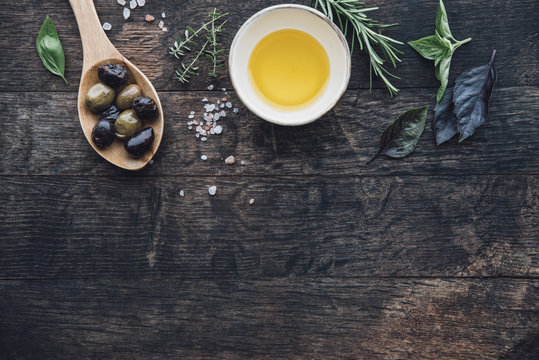 Food: Wooden background with a spoon of olives,himalayan salt,ol