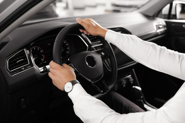 Naklejka premium Young man testing new car in salon