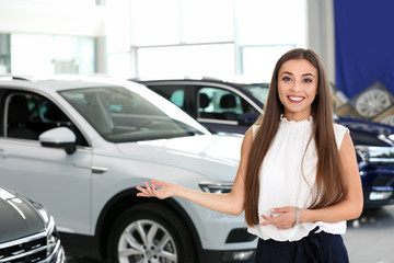 Fototapeta na wymiar Young saleswoman standing in modern car salon