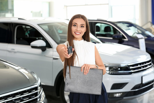 Saleswoman with car key standing in salon