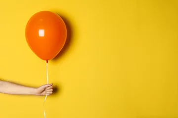 Fotobehang Woman holding orange balloon on color background © New Africa