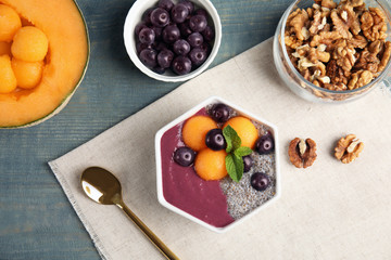 Flat lay composition with bowl of tasty acai smoothie on wooden table