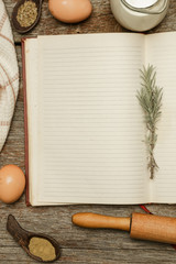 Blank cookbook with some ingredients on the wooden table, top view, rustic style