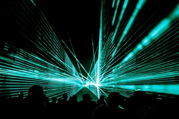 Turquois laser show nightlife club stage with party people crowd. Luxury entertainment with audience silhouettes in nightclub event, festival or New Year's Eve. Beams and rays shining colorful lights - 215894285