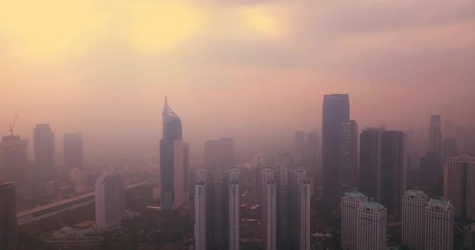 JAKARTA, Indonesia - July 18, 2018: Aerial view of Jakarta central business district with skyscrapers and smog of air pollution at dusk. Shot in 4k resolution