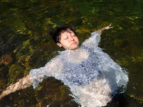 Bare upper body of the woman, lying down into the water