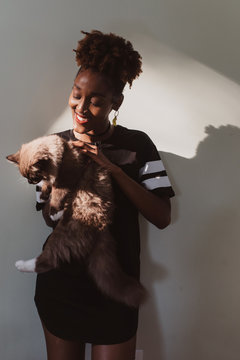 An african american woman at home playing with her cat