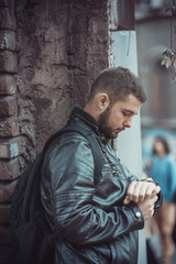 Young man stood up by a friend, impatiently checking his wristwatch, hoping for someone to show up