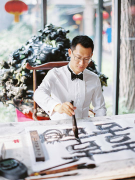 Man drawing with ink at table