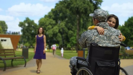 Happy son hugging father in wheelchair injured soldier meeting family homecoming