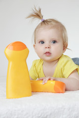 Studio portrait of adorable baby girl with cream bottles, sunscreen protection cream concept